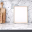 White porcelain countertop and backsplash with dramatic gray marble-look veining, decorative cutting boards, and a blank wood-framed display.